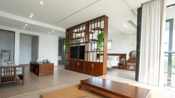 Una sala de estar moderna con un mueble de madera para entretenimiento, un sofá, una mesa de centro y un televisor.