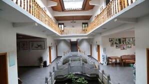 Ein geräumiger Innenhof mit einer zentralen Treppe, Holzgeländern und einem kleinen Wasserspiel.