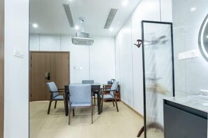 A modern meeting room with a wooden door, a round table, and four chairs. - Liuxi Hostel (Jing County)