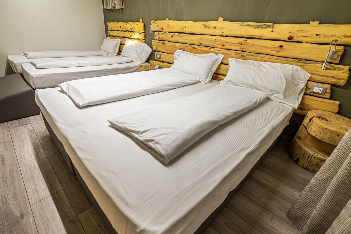 Une chambre avec trois lits simples, des têtes de lit en bois et un plancher en bois.