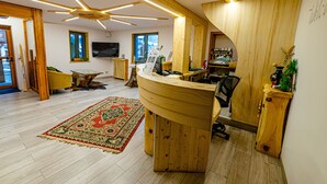 Un interior moderno con un mostrador de recepción de madera, una alfombra grande y un ventilador de techo.