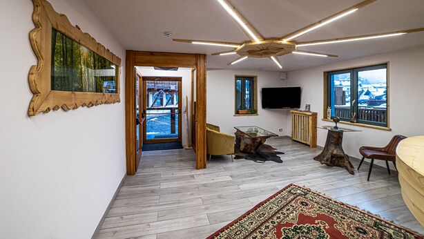 Un salón amplio con ventilador de techo de madera, un ventanal con vistas y un televisor montado.