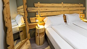 Un dormitorio con cabecera de madera, un espejo grande, una mesita de noche y una cama con ropa blanca.