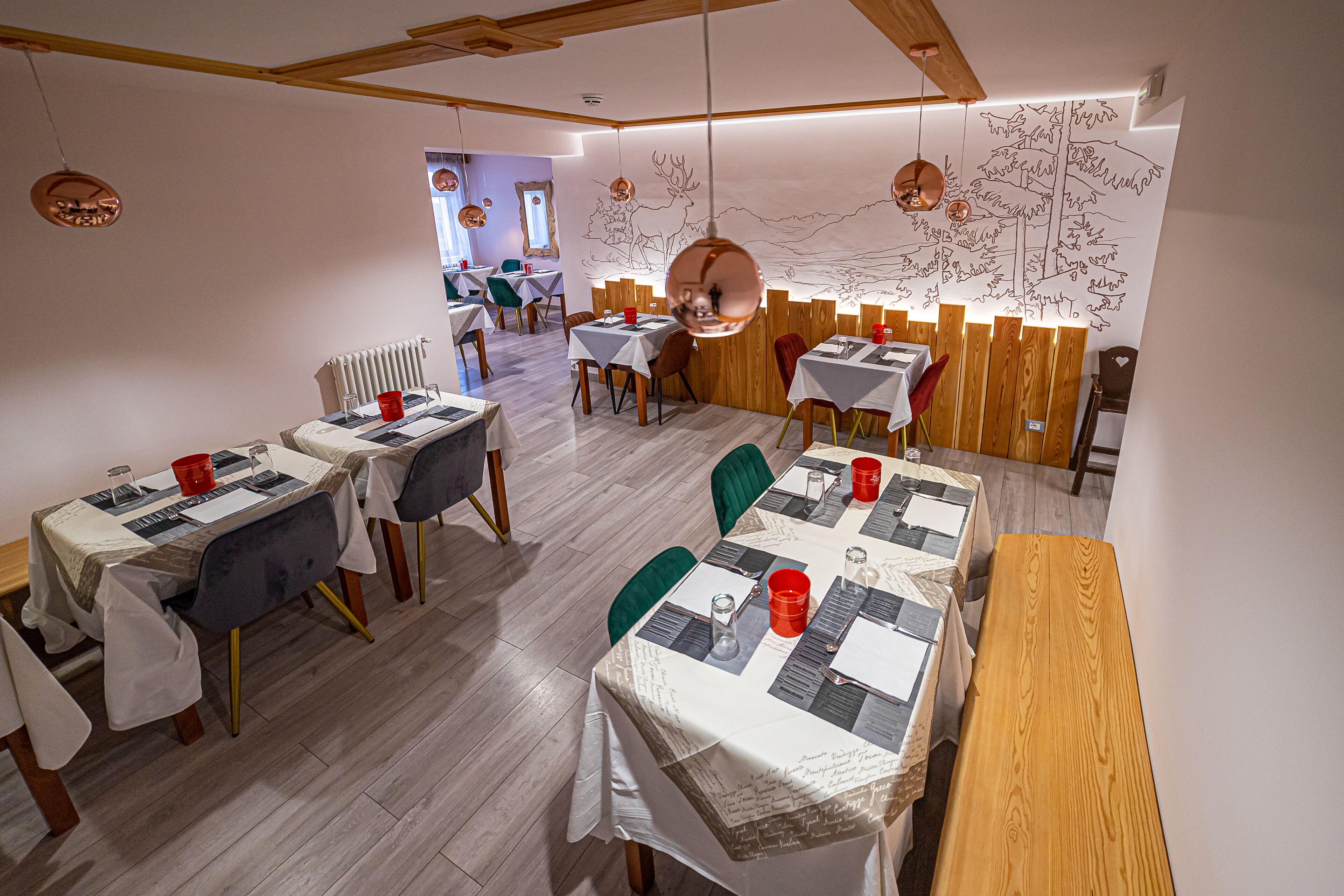 Ein Restaurant mit Holztischen und -stühlen, weißen Tischdecken und roten Bechern.
