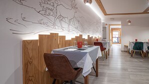 Un comedor con separadores de madera, mesas con manteles blancos y sillas.