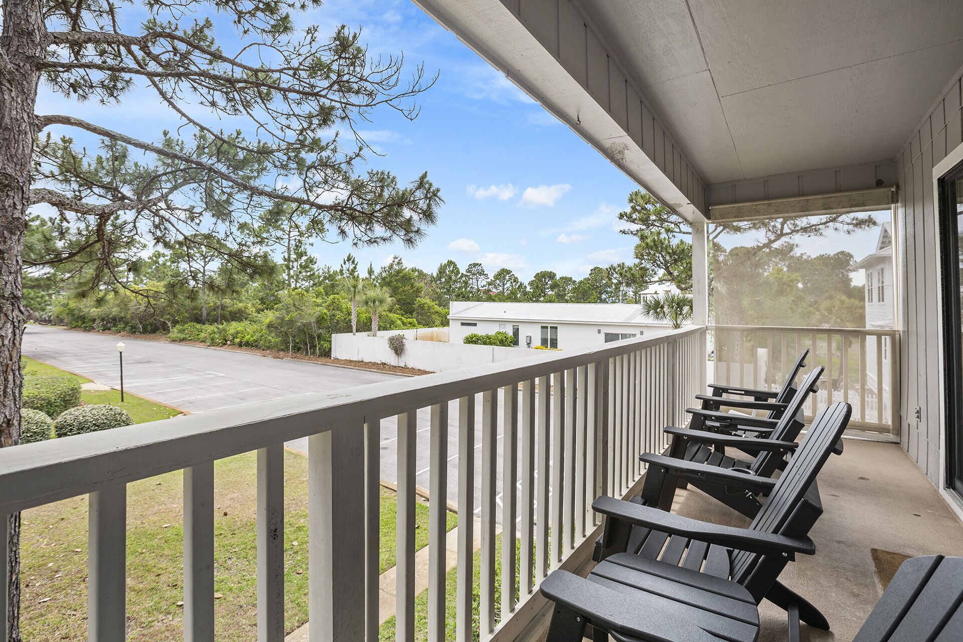 A covered outdoor seating area with a view of a parking lot and a building in the background.