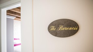 A sign on a wall that reads "The Baroness." - The Baroness Apartment   Lady Capulet (Verona)
