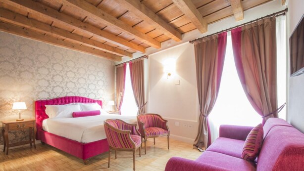 A bedroom with a bed, a chair, a sofa, and a nightstand. - The Baroness Apartment   Lady Capulet (Verona)