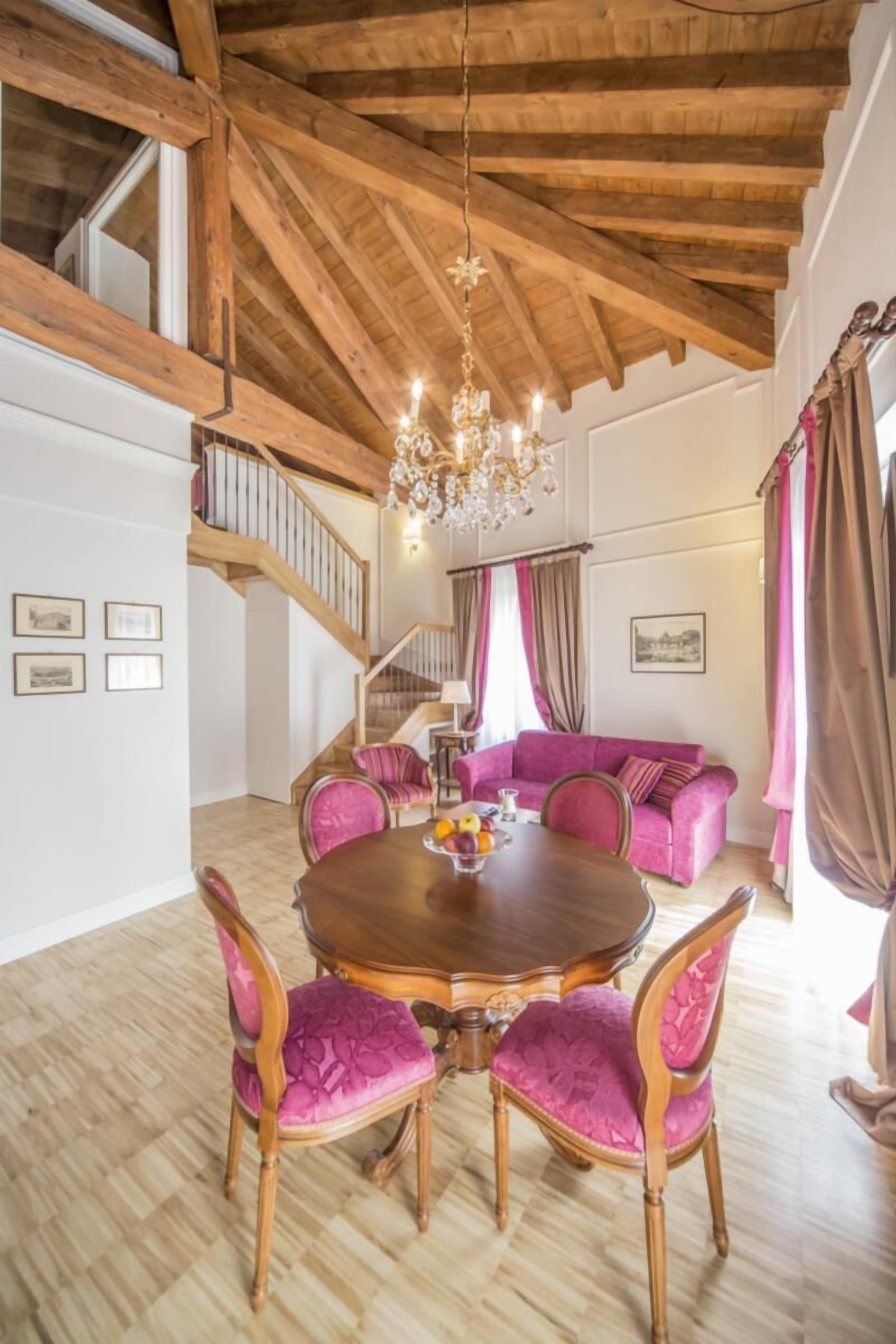 Ein Essbereich mit Holztisch und Stühlen, einer Chandelüster und einer Treppe, die in ein Obergeschoss führt.