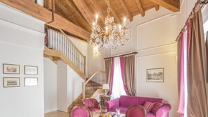 A dining area with a wooden table and chairs, a chandelier, and a staircase leading to an upper level.