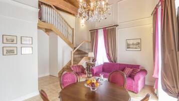 Ein Essbereich mit Holztisch und Stühlen, einer Chandelüster und einer Treppe, die in ein Obergeschoss führt.