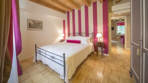 Une chambre à coucher avec un lit, un plancher en bois et un couloir menant à une autre pièce.