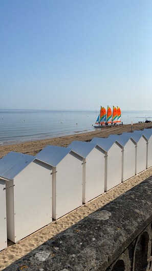 A beach with white beach huts and colorful sailboats in the background. - Beautiful sea view villa 50m from the beach at Le Home (Varaville)