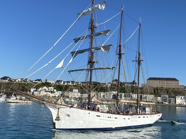 A large sailing ship docked at a harbor with a backdrop of residential buildings. - Beautiful sea view villa 50m from the beach at Le Home (Varaville)