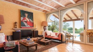 A spacious living room with a fireplace, comfortable seating, and large windows offering a view of the outdoors. - Fantastic Rural Villa Korema: 8 pax Between SHorta and Portocolom (Portocolom)
