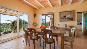 A dining area with a large table and chairs, a painting on the wall, and a view through the glass doors. - Fantastic Rural Villa Korema: 8 pax Between SHorta and Portocolom (Portocolom)