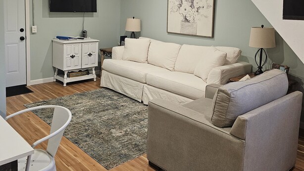 A living room with a sofa, a coffee table, a TV, and a staircase. - The Wee Nook, just 3 miles from Carver Landing! (Piercetown)
