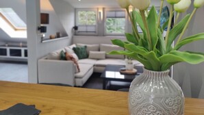 En moderne stue med en hvid sofa, et sofabord og en vase med hvide tulipaner.