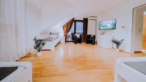 Un salon moderne avec un plancher en bois, un canapé, un téléviseur et un escalier menant à un niveau supérieur.
