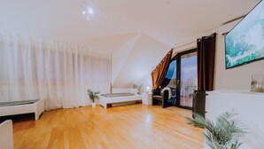 Une chambre moderne avec un plancher en bois, un lit, un bureau, une chaise et une plante en pot.