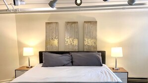 Une chambre à coucher comprenant un lit, deux tables de chevet et trois lampes fixées au mur.