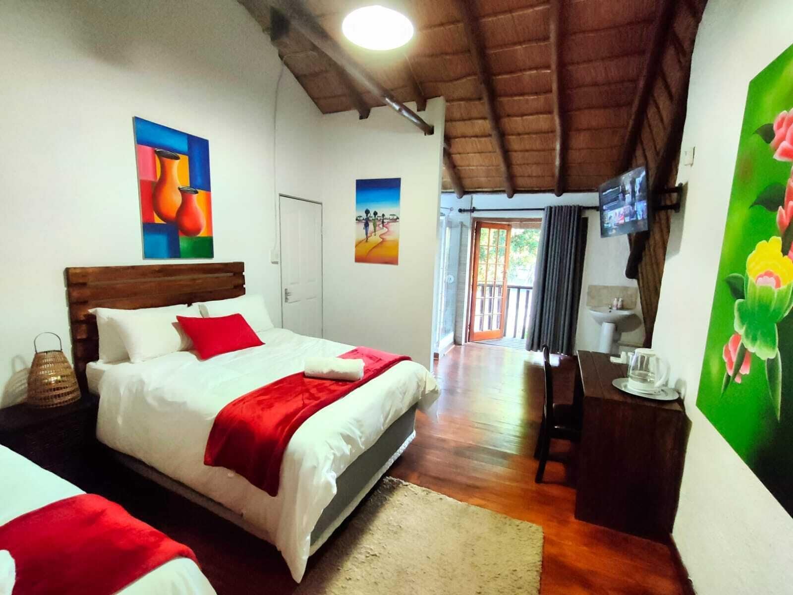 Habitación de hotel con cama, escritorio, silla, televisión y obras de arte en las paredes.