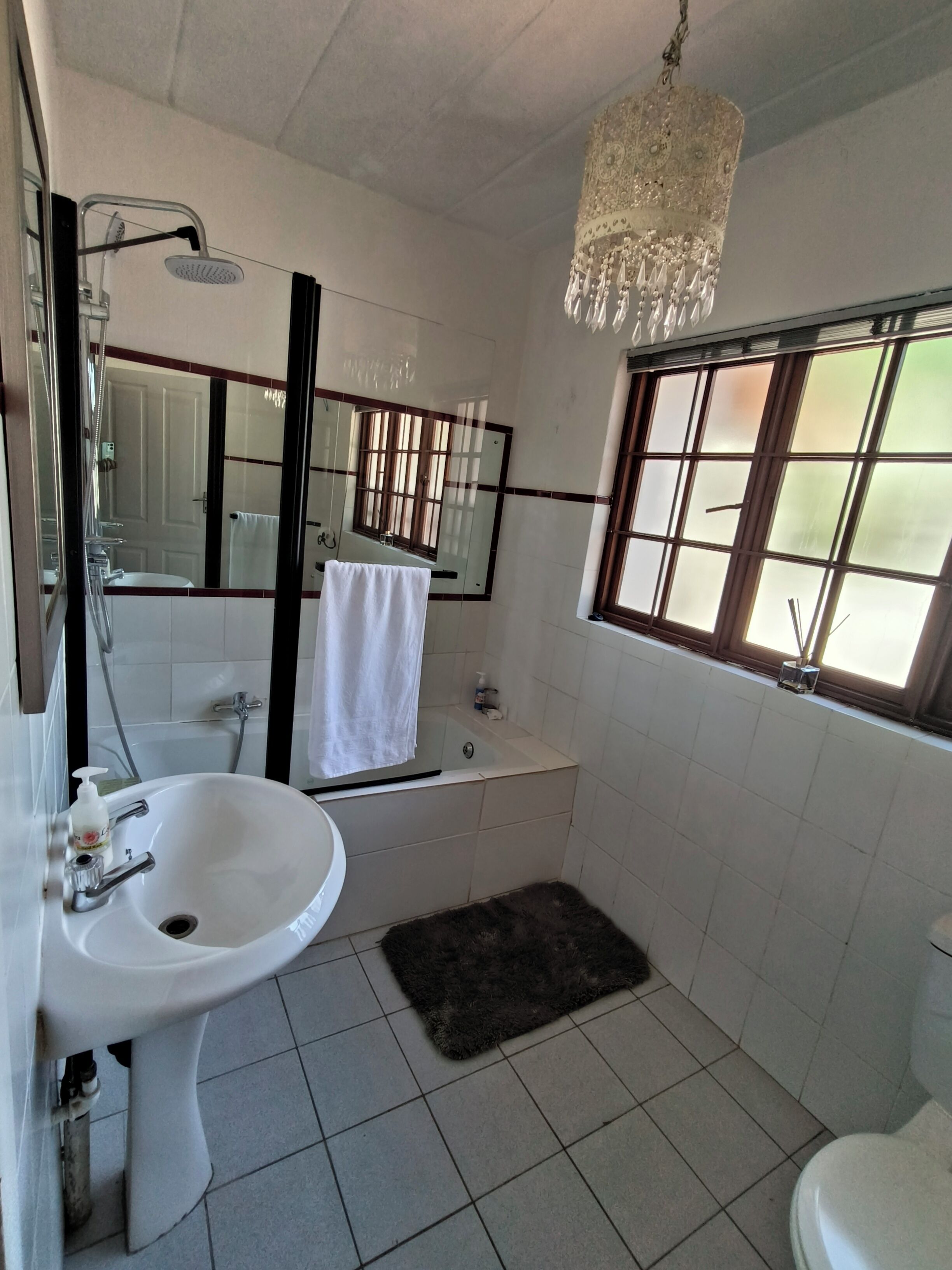 Ein Badezimmer mit Waschbecken, Spiegel, Dusche und Fenster.