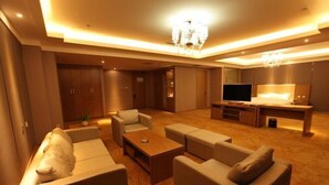 Un soggiorno moderno con divani, un tavolino, una TV e un lampadario.