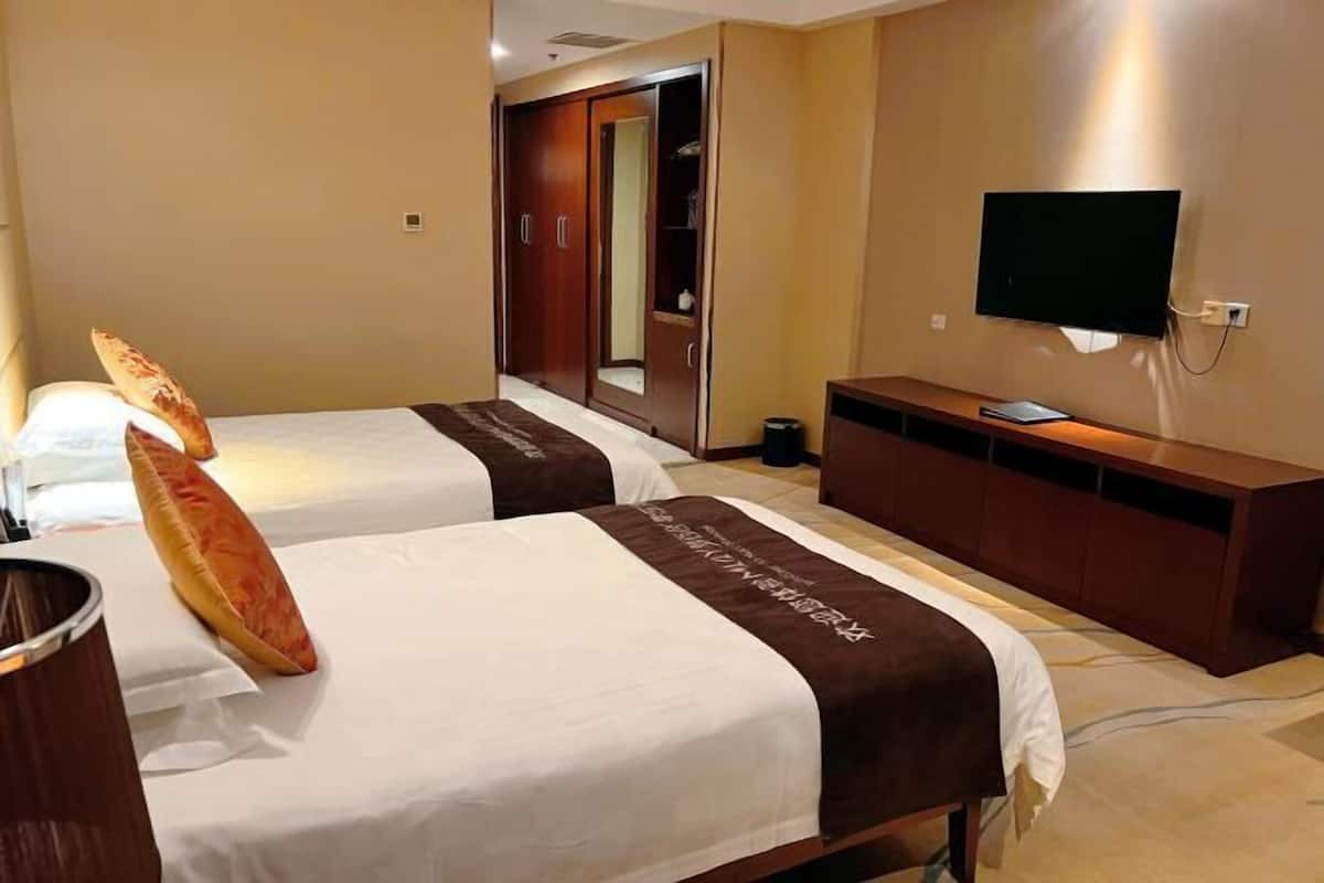 Ett hotellrum med två sängar, en TV, en garderob och en spegel.