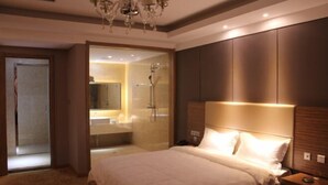 Una camera da letto con un letto grande, un comodino, uno specchio e un bagno visibile attraverso una porta in vetro.