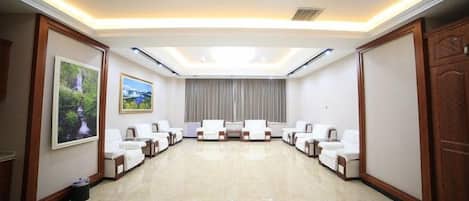 A conference room with a long table and multiple chairs, a large window with curtains, and a wooden door.