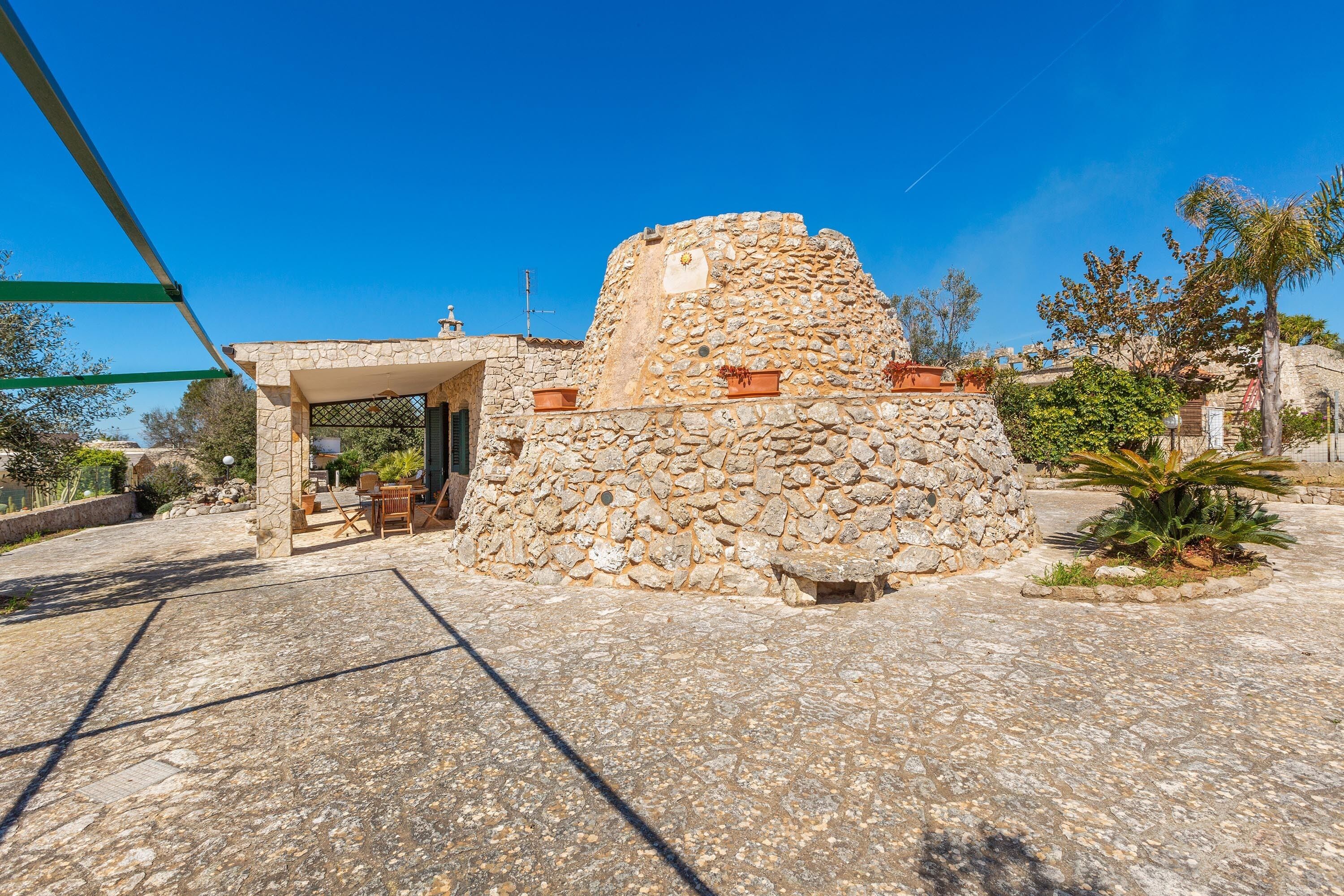 Ein Steinhaus mit kleiner Terrasse und Sitzgelegenheiten im Freien.