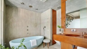 Un baño moderno con una bañera independiente, un tocador de madera y un espejo grande.