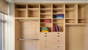 Un vestidor amplio con múltiples estantes y cajones, algunos con ropa doblada.