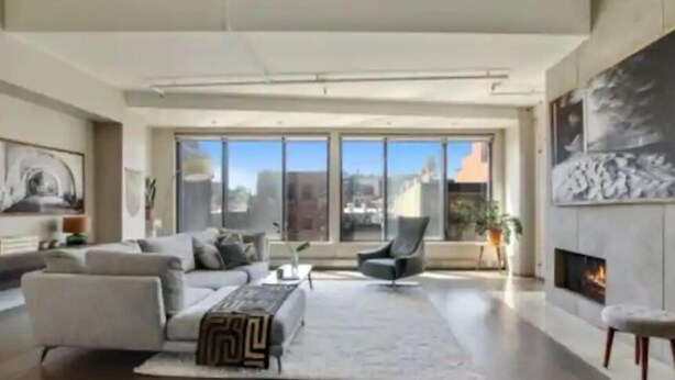 Amplia sala de estar con un gran ventanal, chimenea y muebles modernos.