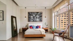 Un dormitorio moderno con una cama grande, vistas a la ciudad y un cuadro abstracto de gran tamaño en la pared.