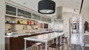 Una cocina moderna con una isla central, taburetes de bar y un colgador de luces.