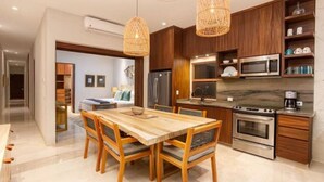 Una cocina moderna con armarios de madera, electrodomésticos de acero inoxidable y un comedor con mesa y sillas de madera.
