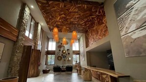 Amplia sala de estar con techo alto, paneles de madera y un largo banco de madera.