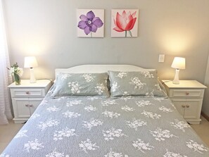 Cozy retreat with a neatly made bed, two nightstands, and framed artwork.