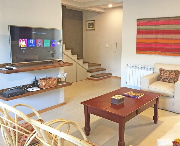Relax in this stylish living room with a flat-screen TV, wooden shelf, and comfortable sofa.