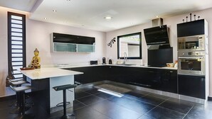 A modern kitchen with black cabinets, a white countertop, and a built-in oven. - La Villa des Mainates - Jacuzzi et vue mer (Le Tampon)