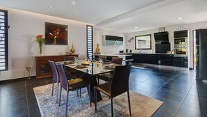 A modern kitchen with built-in appliances and a dining area with a large table and chairs. - La Villa des Mainates - Jacuzzi et vue mer (Le Tampon)