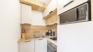 A modern kitchen with white cabinets, a stainless steel sink, a microwave, and an oven.