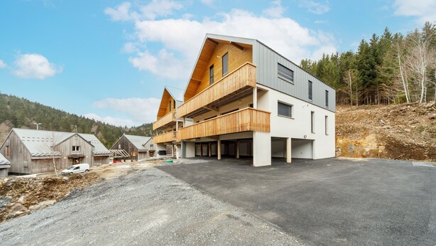 A modern two-story building with a flat roof and a balcony on the upper floor.
