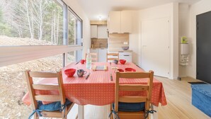 A modern kitchen with wooden cabinets, a dining table with red patterned tablecloths, and chairs.