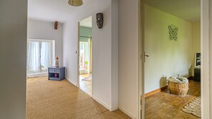 Un couloir doté d’un plancher en bois, d’une armoire bleue et d’une porte donnant sur une autre pièce.