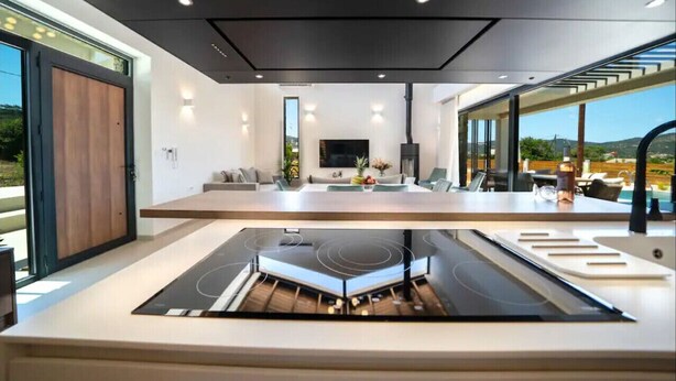 Una cocina moderna con una isla central, electrodomésticos integrados y un amplio ventanal con vistas al exterior.