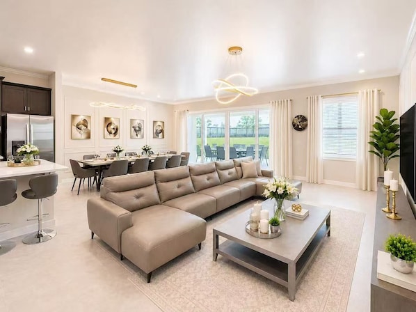 A modern living room with a sectional sofa, dining area, and kitchen.