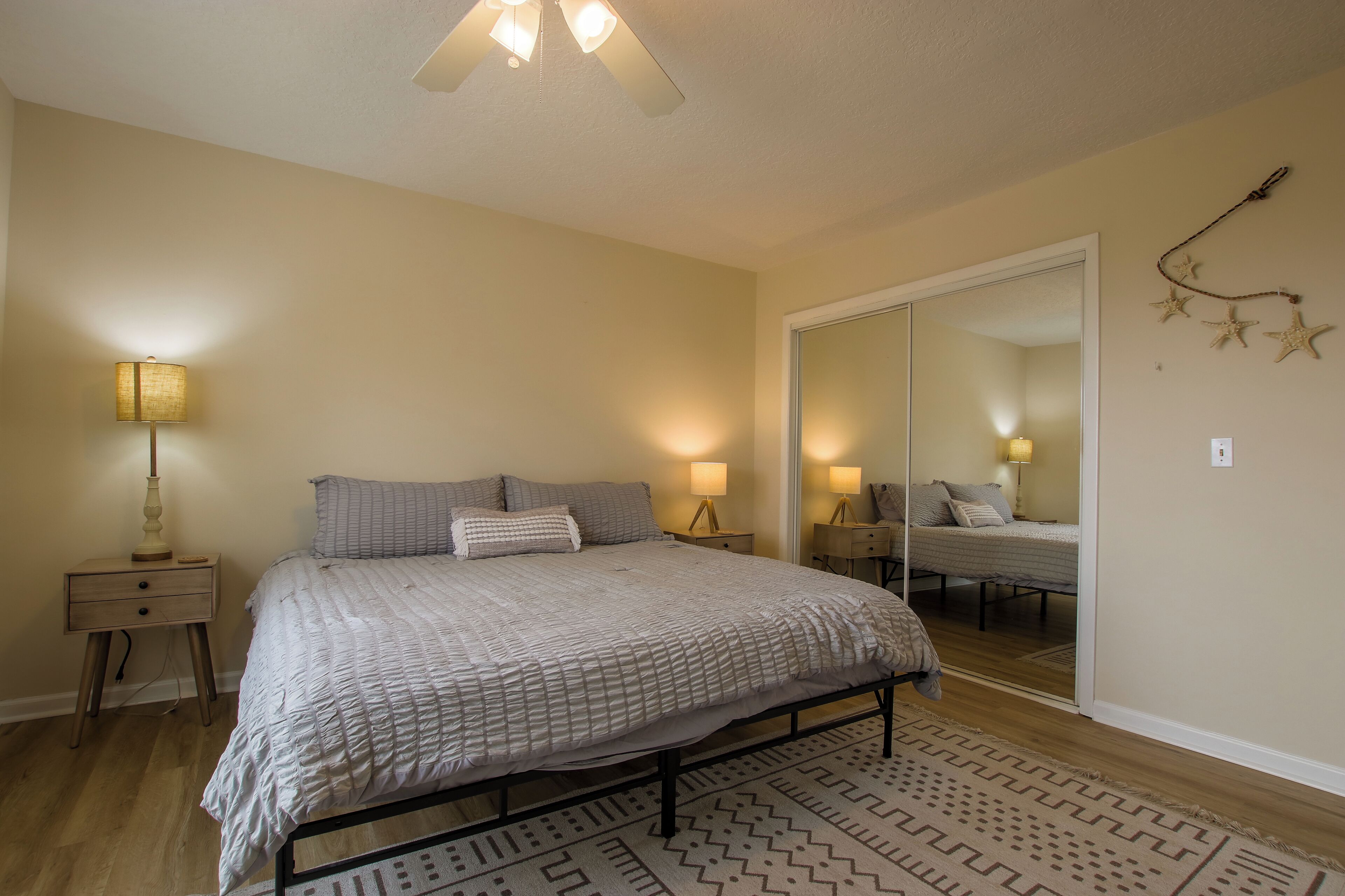 Une chambre à coucher avec un lit, des tables de chevet, un miroir et un tapis à motifs.